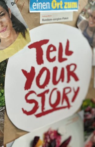 A white paper cutout with the words "TELL YOUR STORY" in bold red letters is pinned to a board, surrounded by magazine photos—capturing the creative energy of a content marketing agency brainstorming ideas and campaigns.